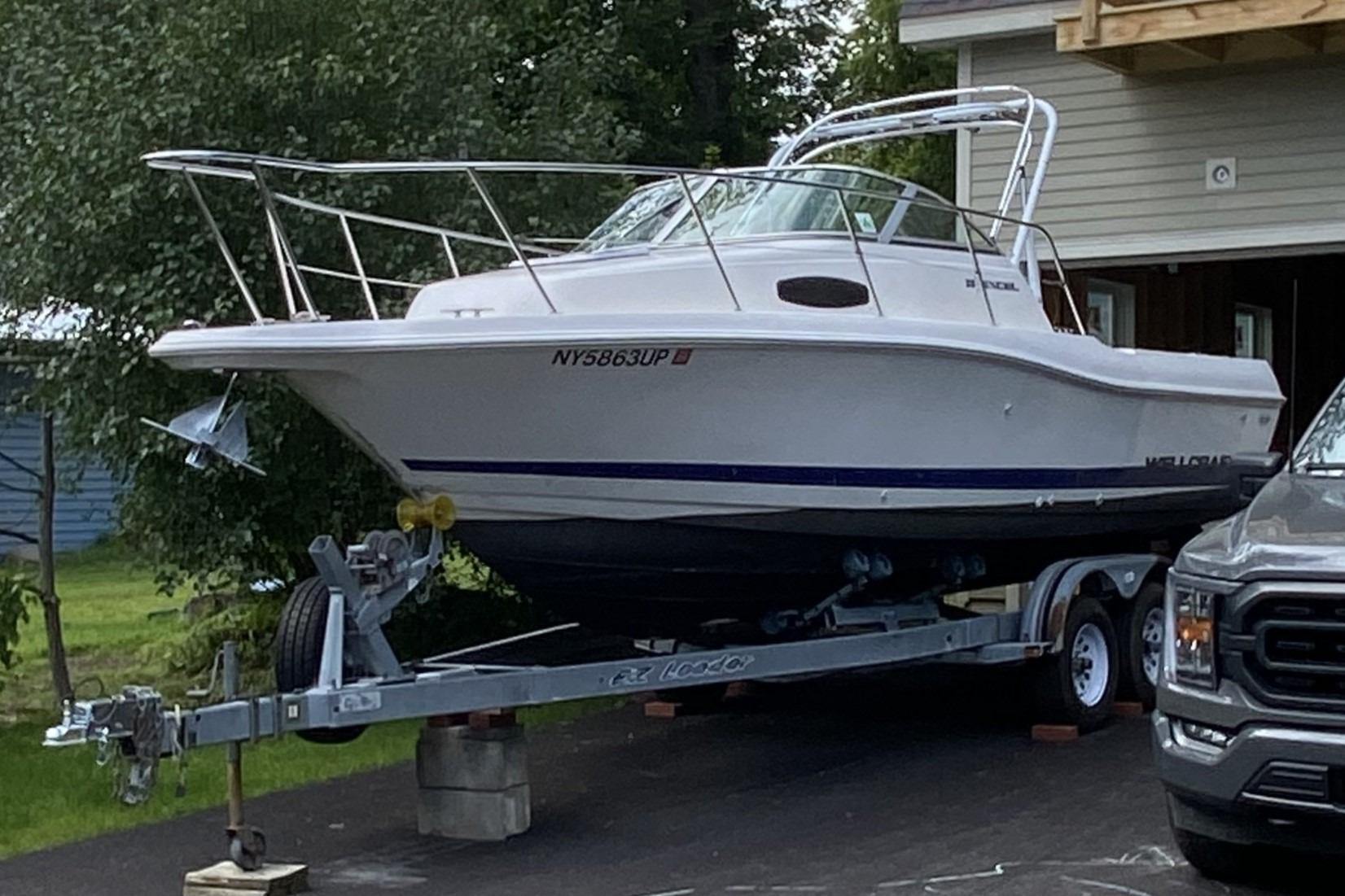 Wellcraft 23 Excel 1996 Wellcraft 23 Excel boat on trailer, parked in driveway near a house.