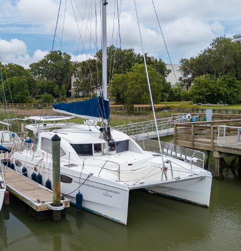 Leopard 39 2012 Leopard 39 catamaran docked at a marina with lush greenery.