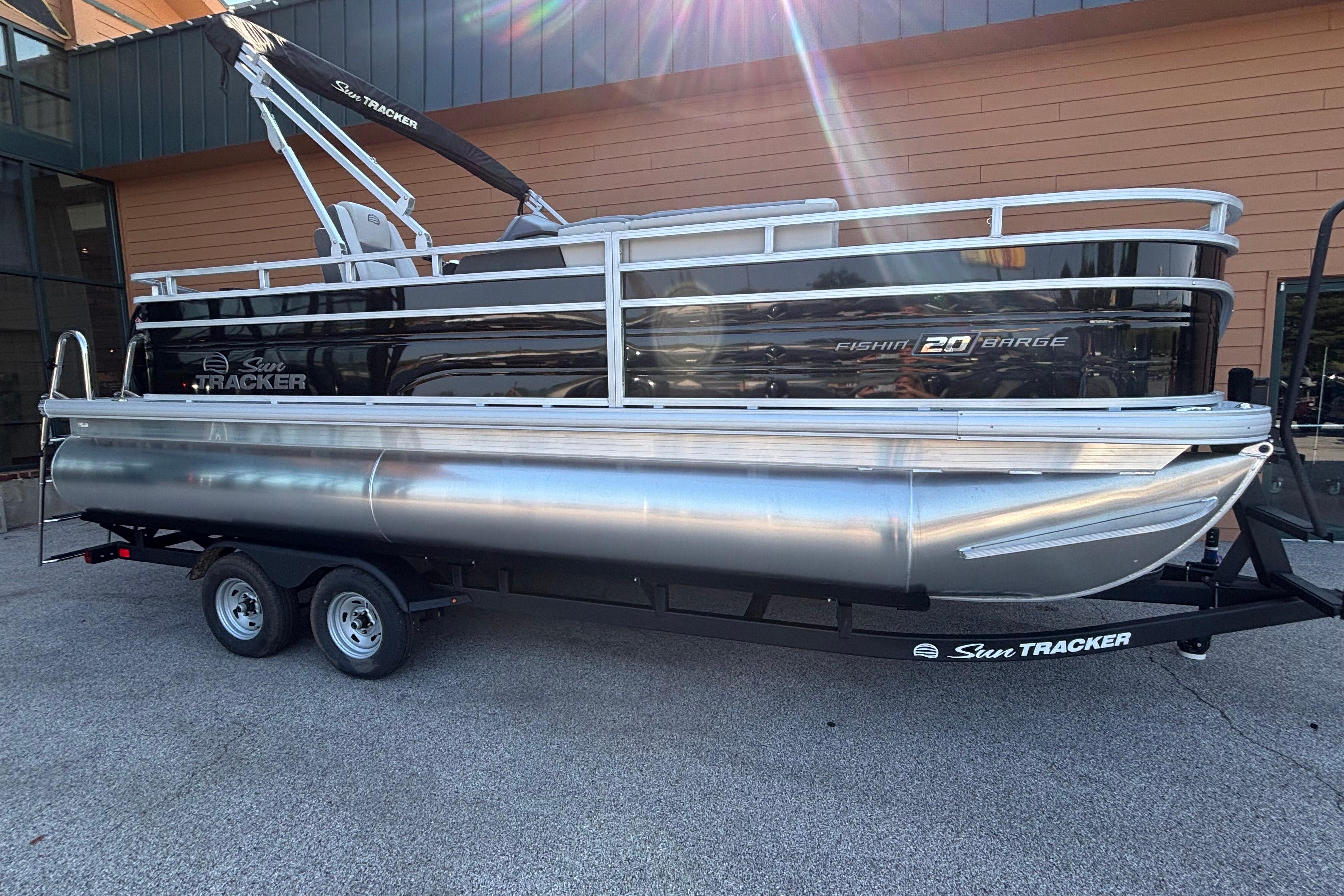 Sun Tracker Fishin' Barge 20 DLX 2026 Sun Tracker Fishin' Barge 20 DLX pontoon boat on trailer, outdoor display.