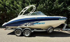 Yamaha Boats AR210 2022 Yamaha AR210 boat on trailer, parked outdoors, surrounded by trees.