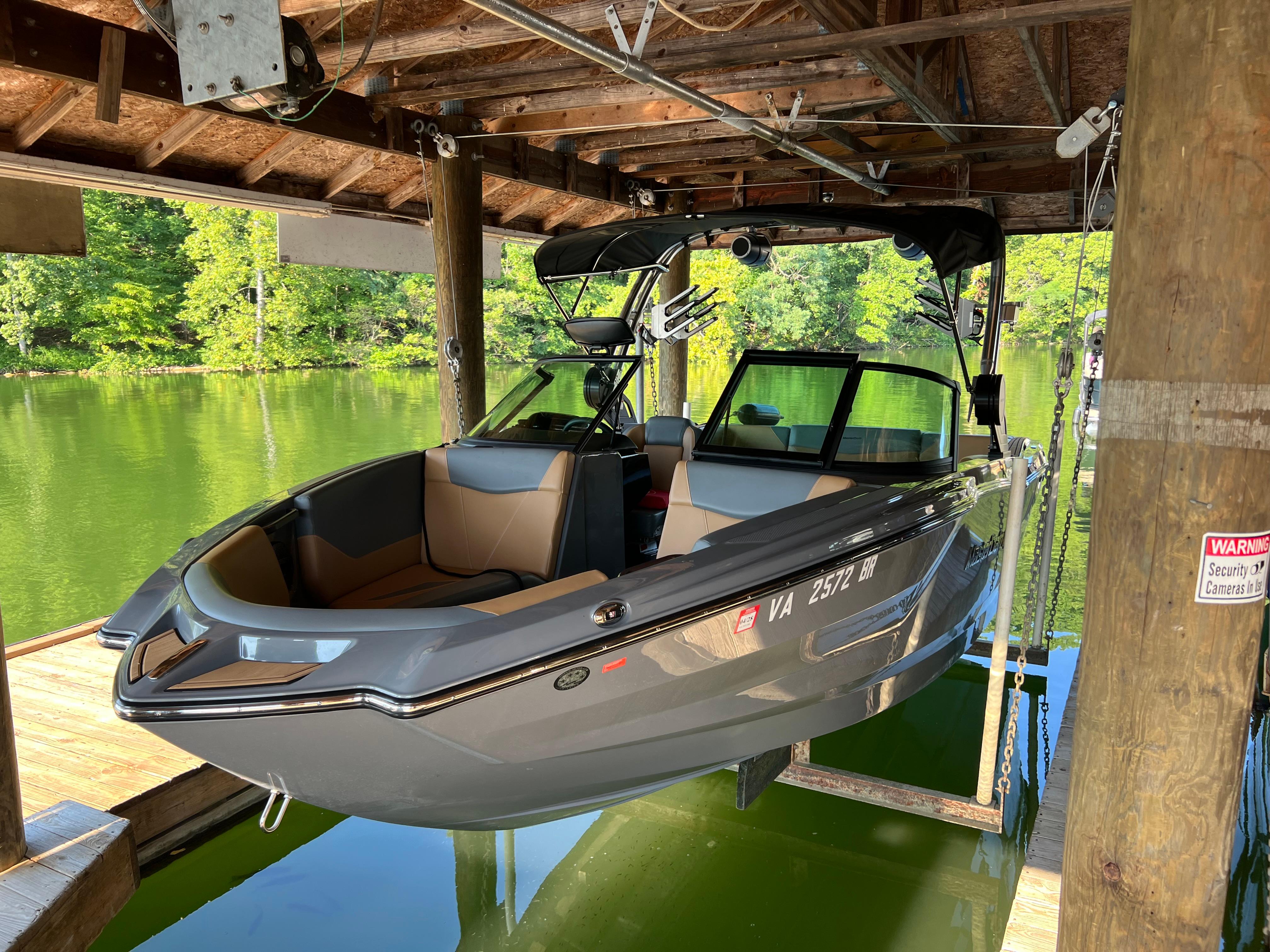 MasterCraft NXT23 2025 MasterCraft NXT23 boat docked in a wooden boathouse over a serene lake.