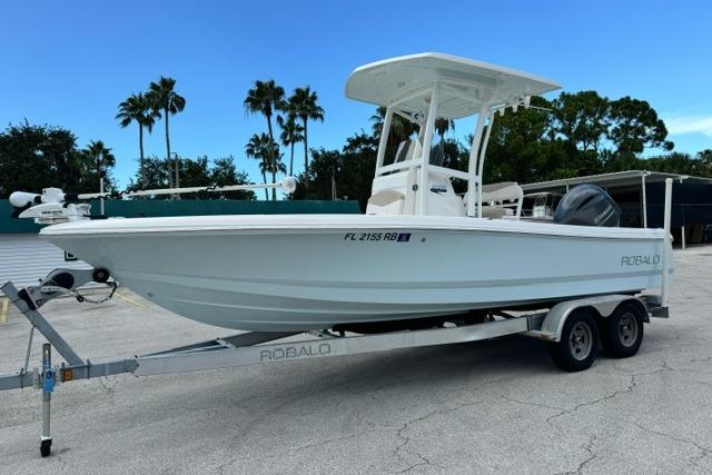 Robalo 226 Cayman 2016 Robalo 226 Cayman boat on trailer, parked outdoors with palm trees in background.