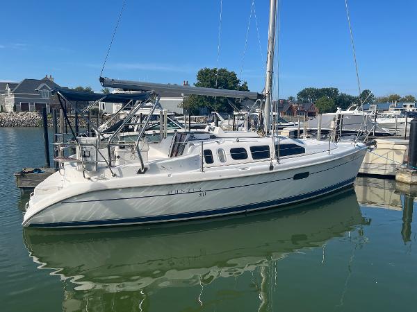 Hunter 310 2000 Hunter 310 sailboat docked in a marina, clear blue sky, calm water.