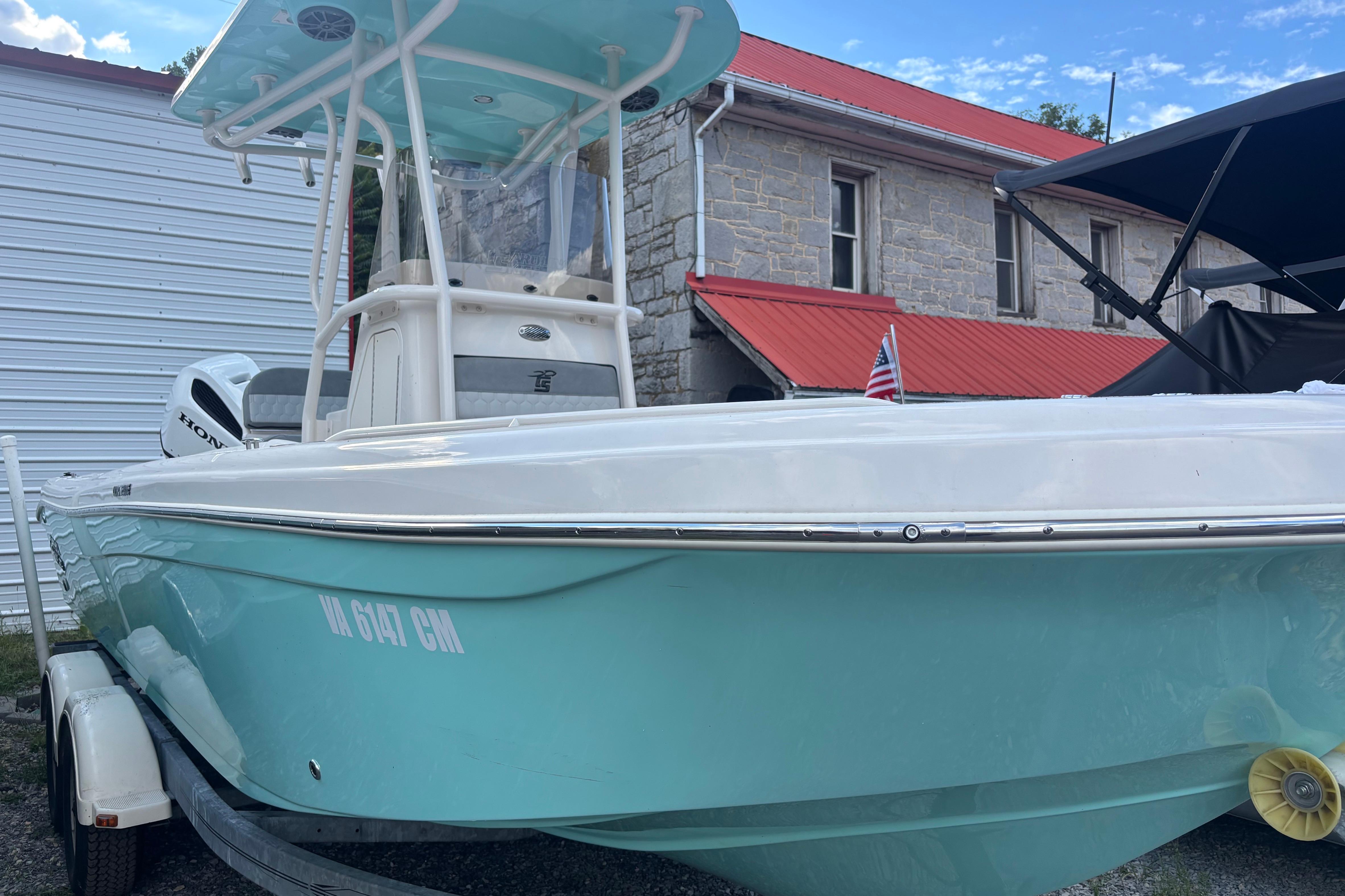 Carolina Skiff 23 Ultra Elite 2025 Carolina Skiff 23 Ultra Elite boat on trailer, light blue hull, parked near building.