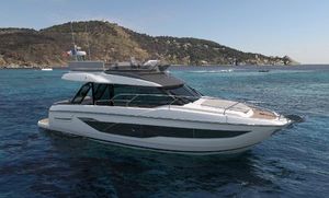 Prestige F4.3 2025 Prestige F4.3 yacht cruising in clear blue waters near a scenic coastline.