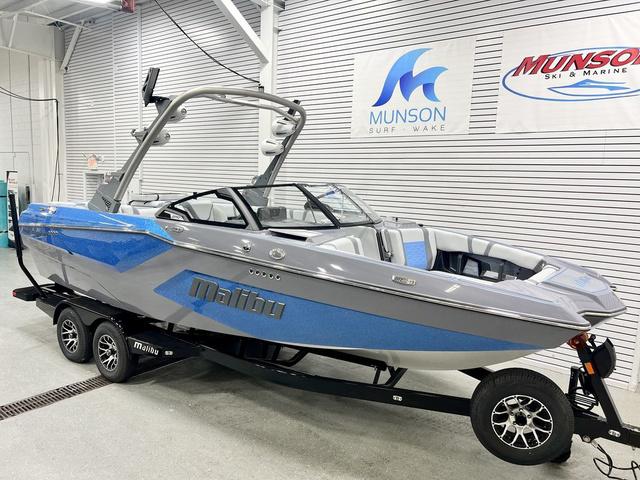 Malibu Wakesetter 23 MXZ 2024 Malibu 23 MXZ boat in showroom, featuring sleek design and blue-gray color scheme.