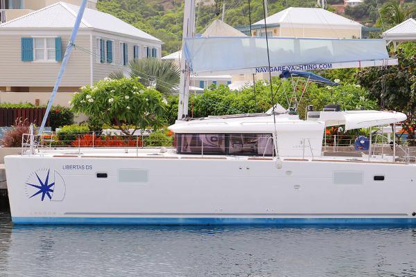 Lagoon 450 F 2019 Lagoon 450 F catamaran docked near tropical houses and lush greenery.