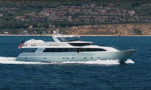 Westport 112 Luxurious 2000 Westport 112 yacht cruising near scenic coastline with hillside homes.