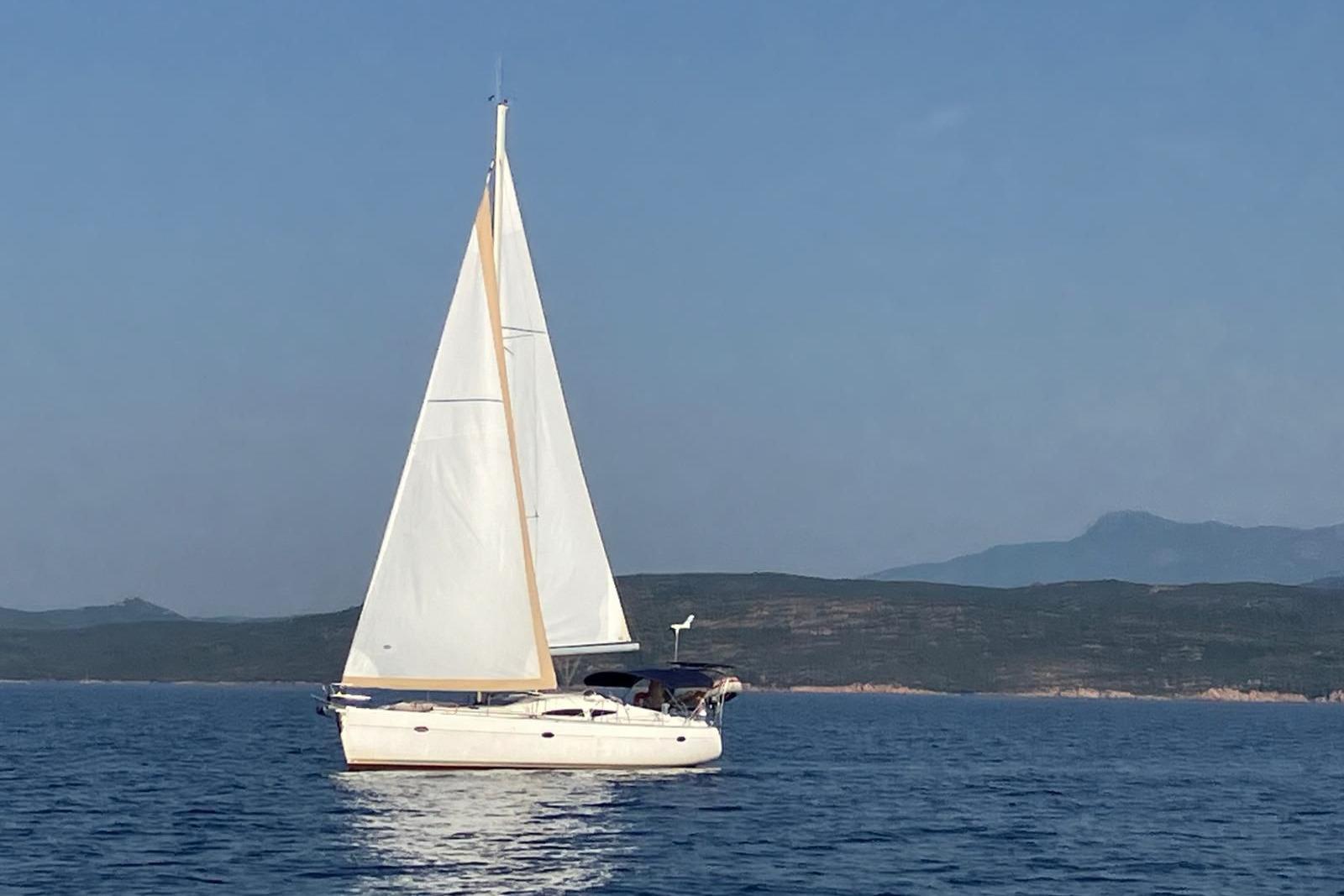 Elan Impression 434 Sailing yacht Elan Impression 434, 2005 model, gliding on calm sea with distant hills.