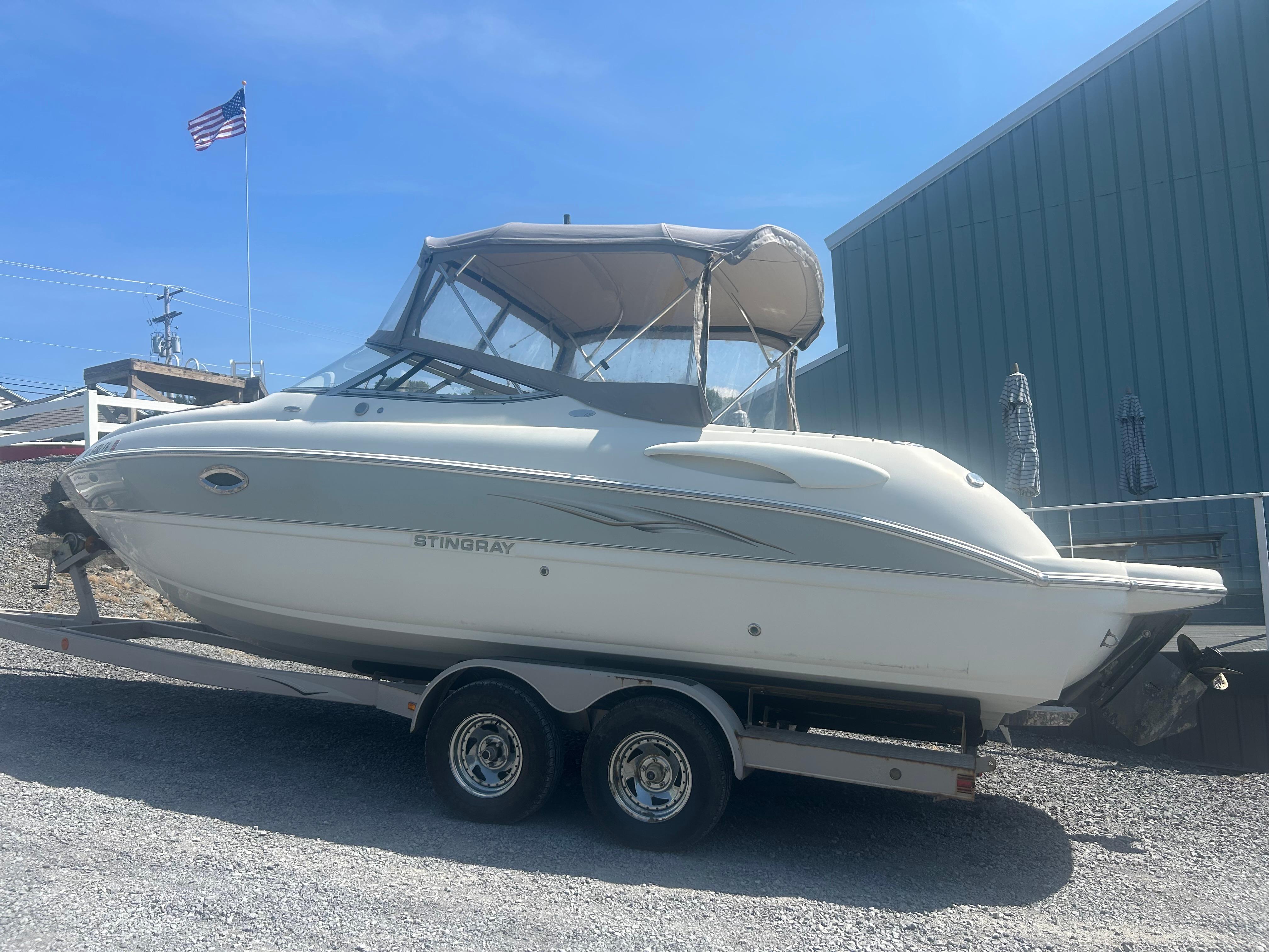 Stingray 250 LR 2005 Stingray 250 LR boat on trailer, parked outdoors under clear blue sky.