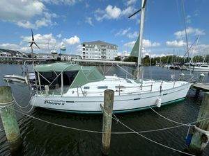 Beneteau 393 2003 Beneteau 393 sailboat docked at marina with green canopy and clear sky.