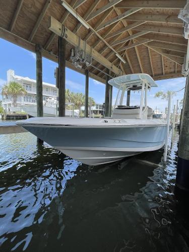 Boston Whaler 220 Dauntless 2022 Boston Whaler 220 Dauntless boat docked under a wooden shelter.