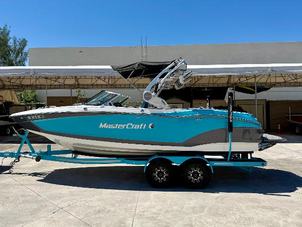 MasterCraft X22 2019 MasterCraft X22 boat on trailer, turquoise and gray, parked outdoors.