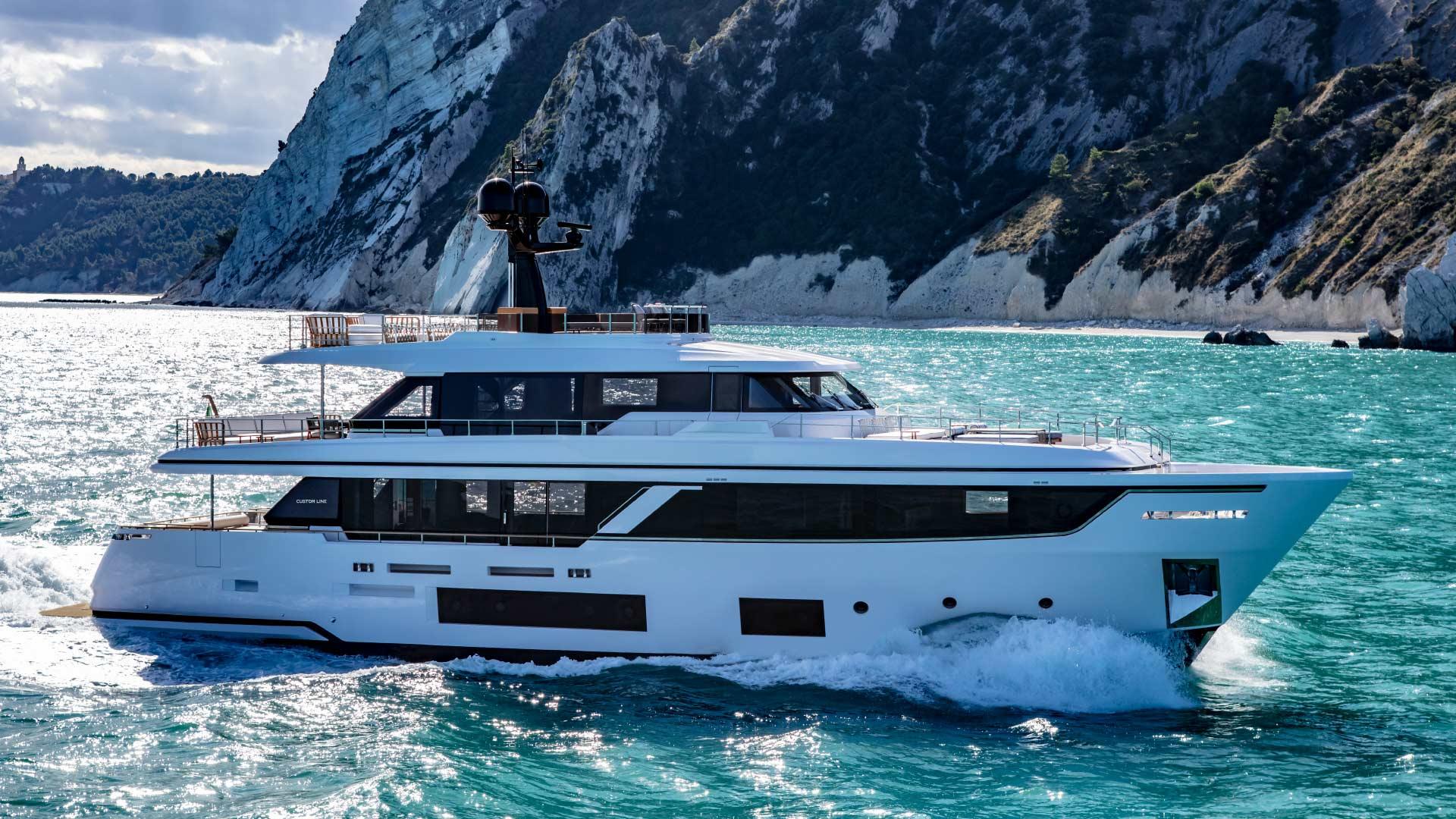 Custom Line Navetta 30 Luxurious 2022 Custom Line Navetta 30 yacht cruising near rocky coastline.