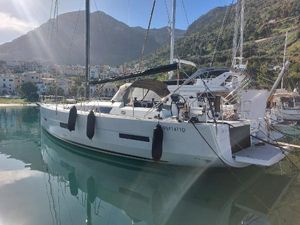Dufour 56 Exclusive Premium Dufour 56 Exclusive Premium 2020 yacht docked in scenic marina with mountain backdrop.