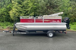 Sun Tracker Bass Buggy 16 XL Select 2025 Sun Tracker Bass Buggy 16 XL Select pontoon boat on trailer, surrounded by lush greenery.