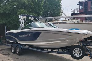 MasterCraft X26 2016 MasterCraft X26 boat on a trailer, parked near other boats and trees.