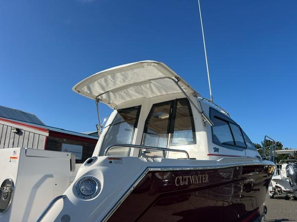 Cutwater C-242 Coupe 2018 Cutwater C-242 Coupe boat with canopy, docked under clear blue sky.