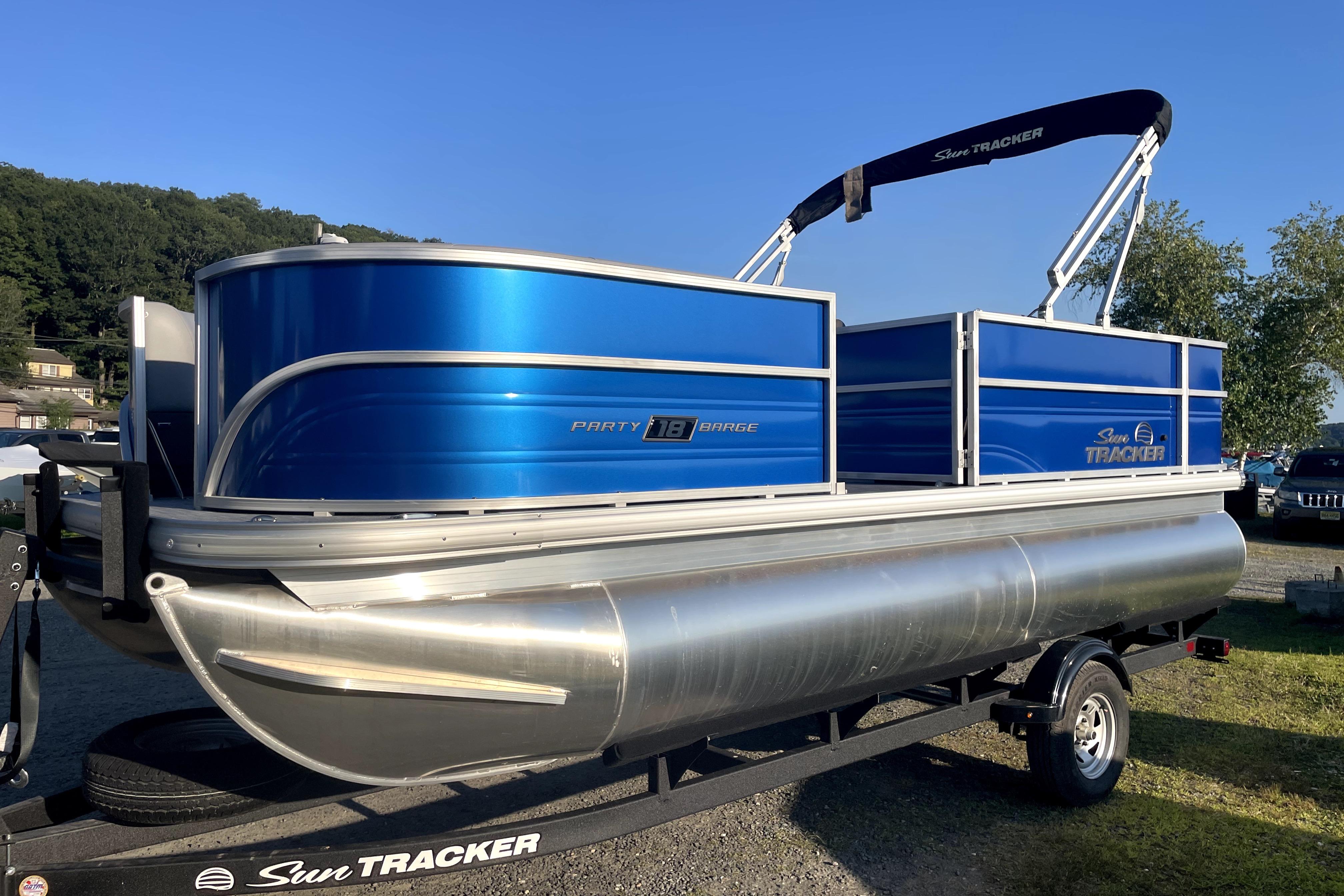 Sun Tracker Party Barge 18 DLX 2026 Sun Tracker Party Barge 18 DLX pontoon boat on trailer, blue and silver design.