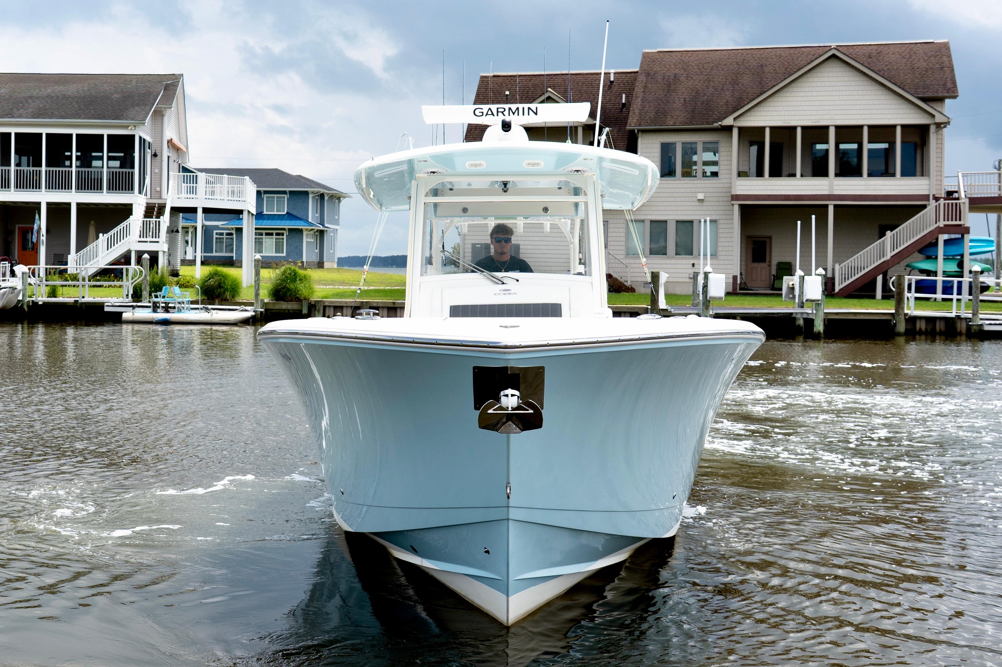 Cobia 350 2024 Cobia 350 boat navigating a canal with waterfront homes in the background.