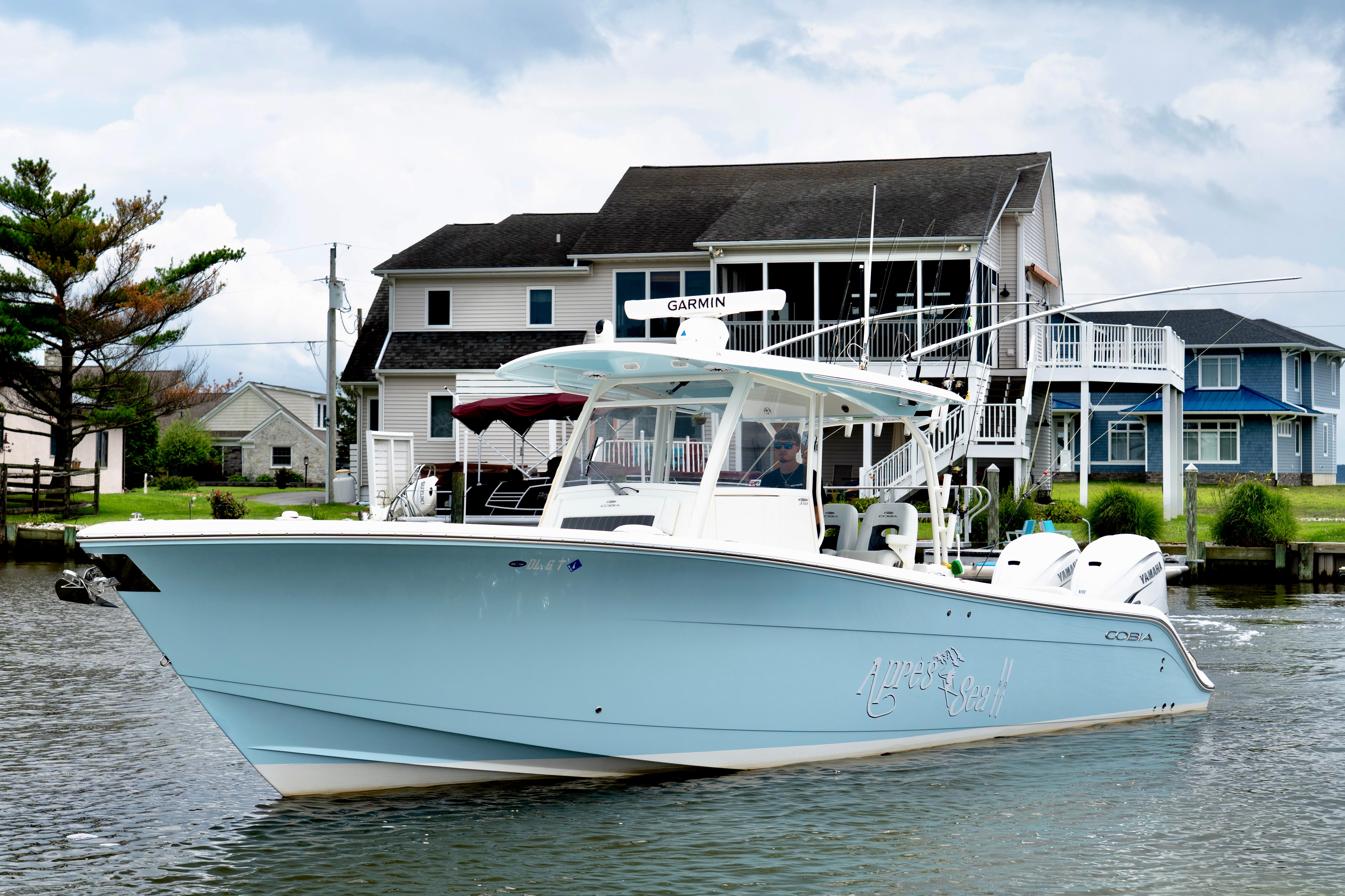 Cobia 350 Center Console 2024 Cobia 350 boat cruising near waterfront homes under a cloudy sky.