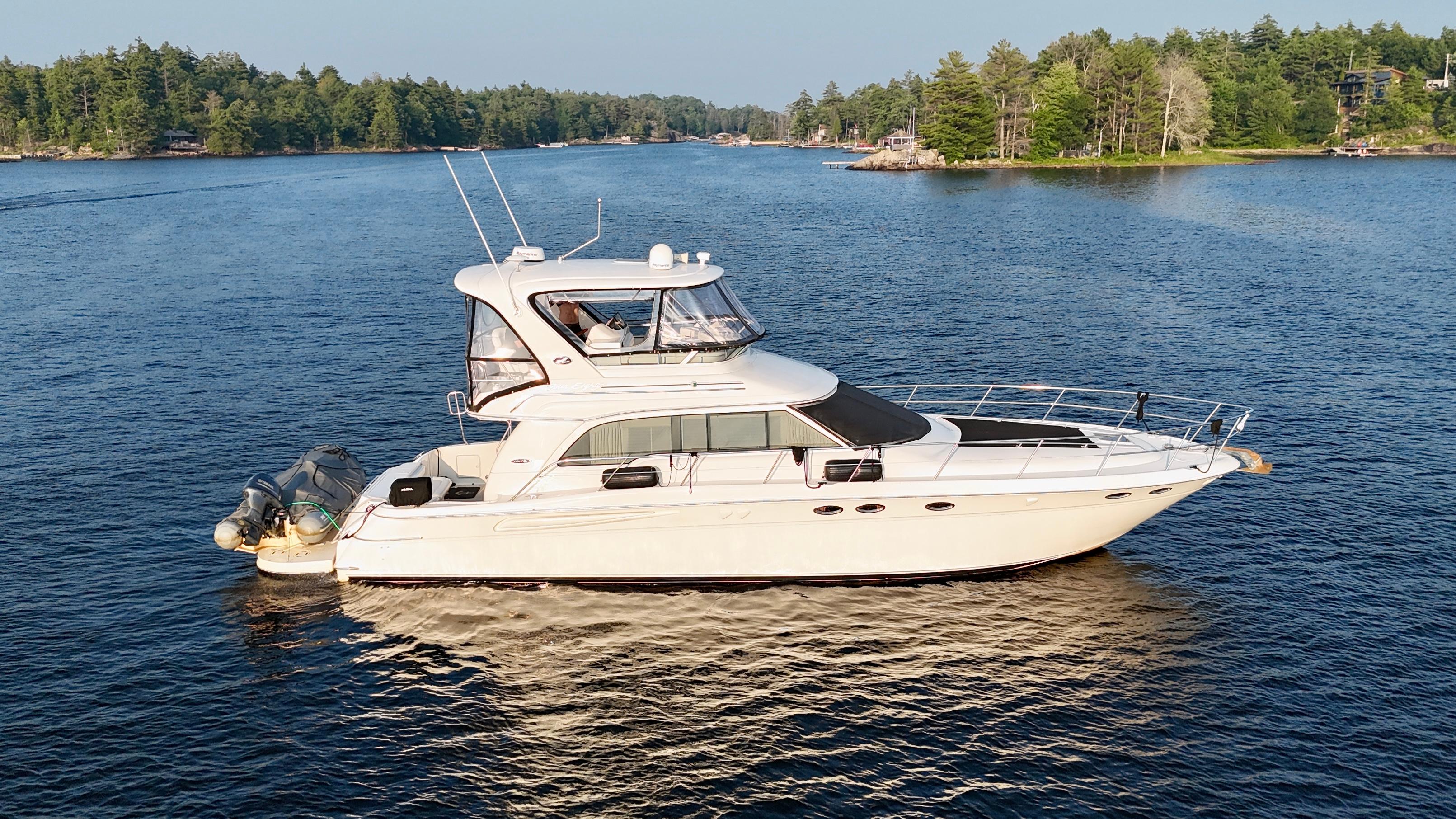Sea Ray 480 Sedan Bridge 2001 Sea Ray 480 Sedan Bridge yacht on a serene lake with forested shoreline.