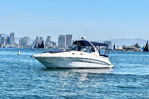 Sea Ray 320 Sundancer Sea Ray 320 Sundancer 2004 cruising in a harbor with city skyline backdrop.