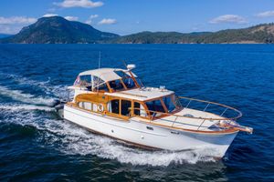 Monk Triple Deck Cruiser 1958 Monk Triple Deck Cruiser sailing on blue ocean with scenic mountain backdrop.