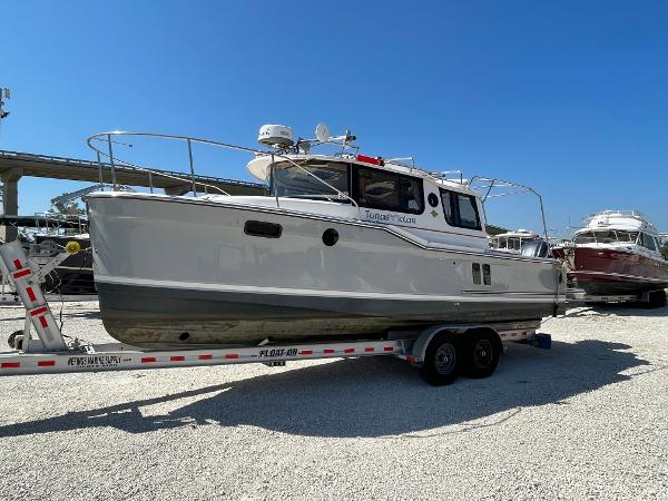 Ranger Tugs R-27 2023 Ranger Tugs R-27 boat on trailer, parked outdoors under clear blue sky.