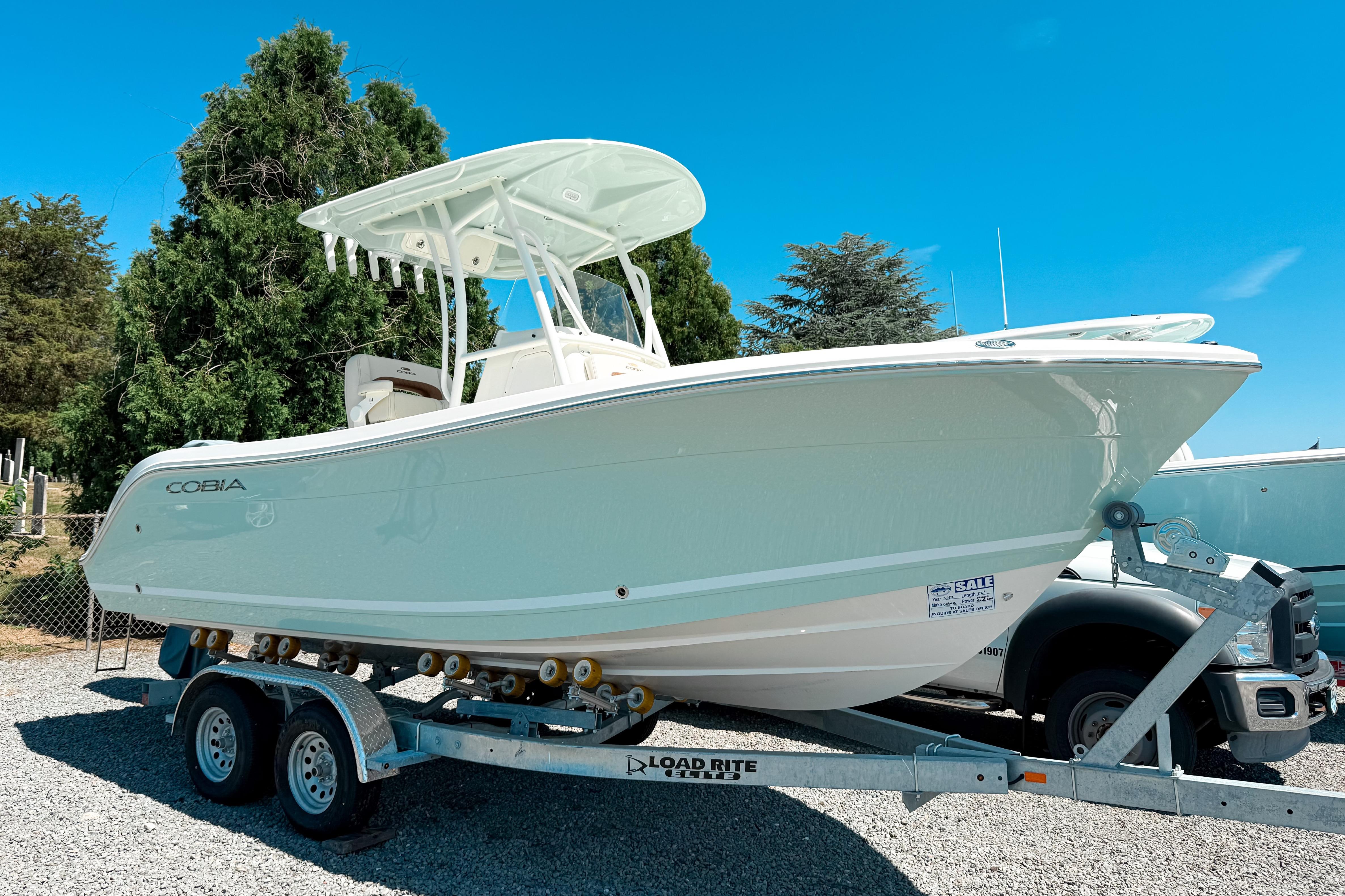 Cobia 220 Center Console 2025 Cobia 220 Center Console boat on trailer, parked outdoors under clear blue sky.