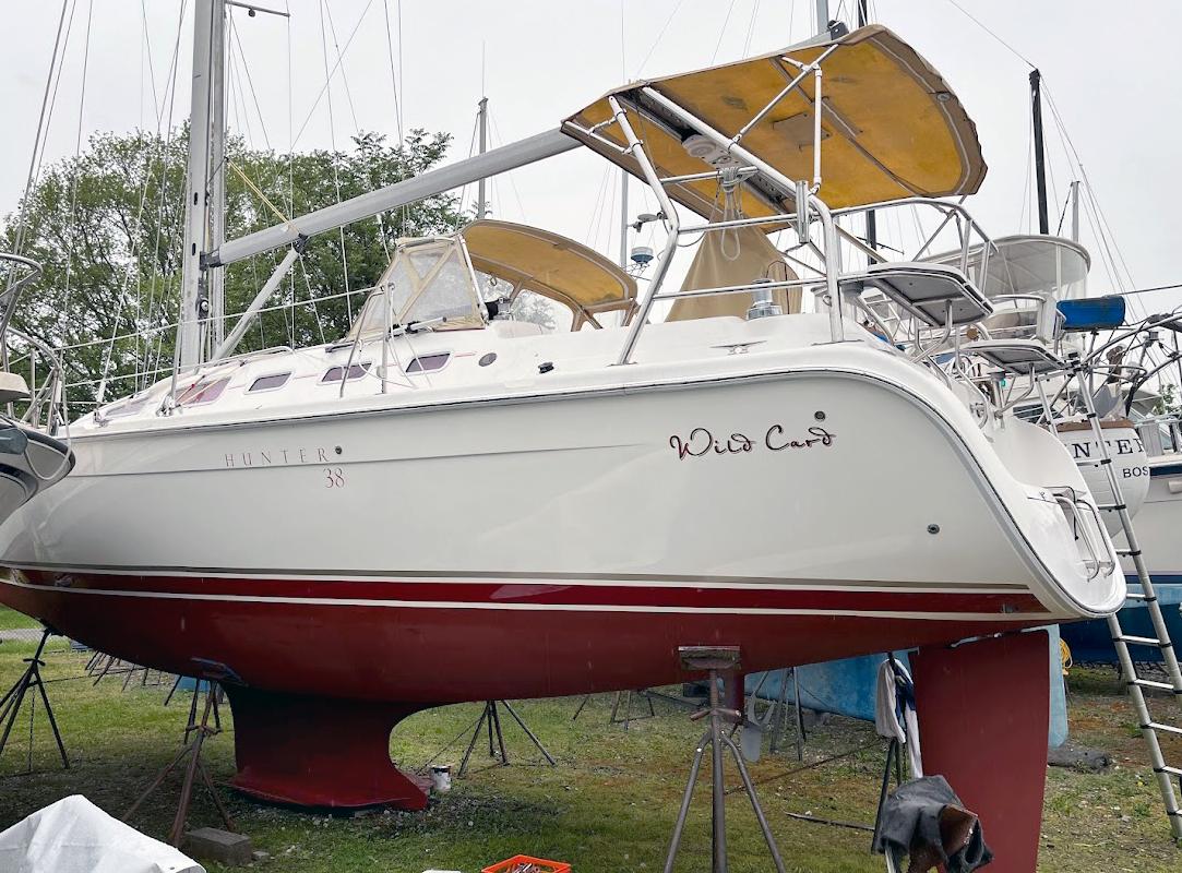 Hunter 38 2005 Hunter 38 sailboat on stands, named "Wild Card," with red hull and yellow canopy.
