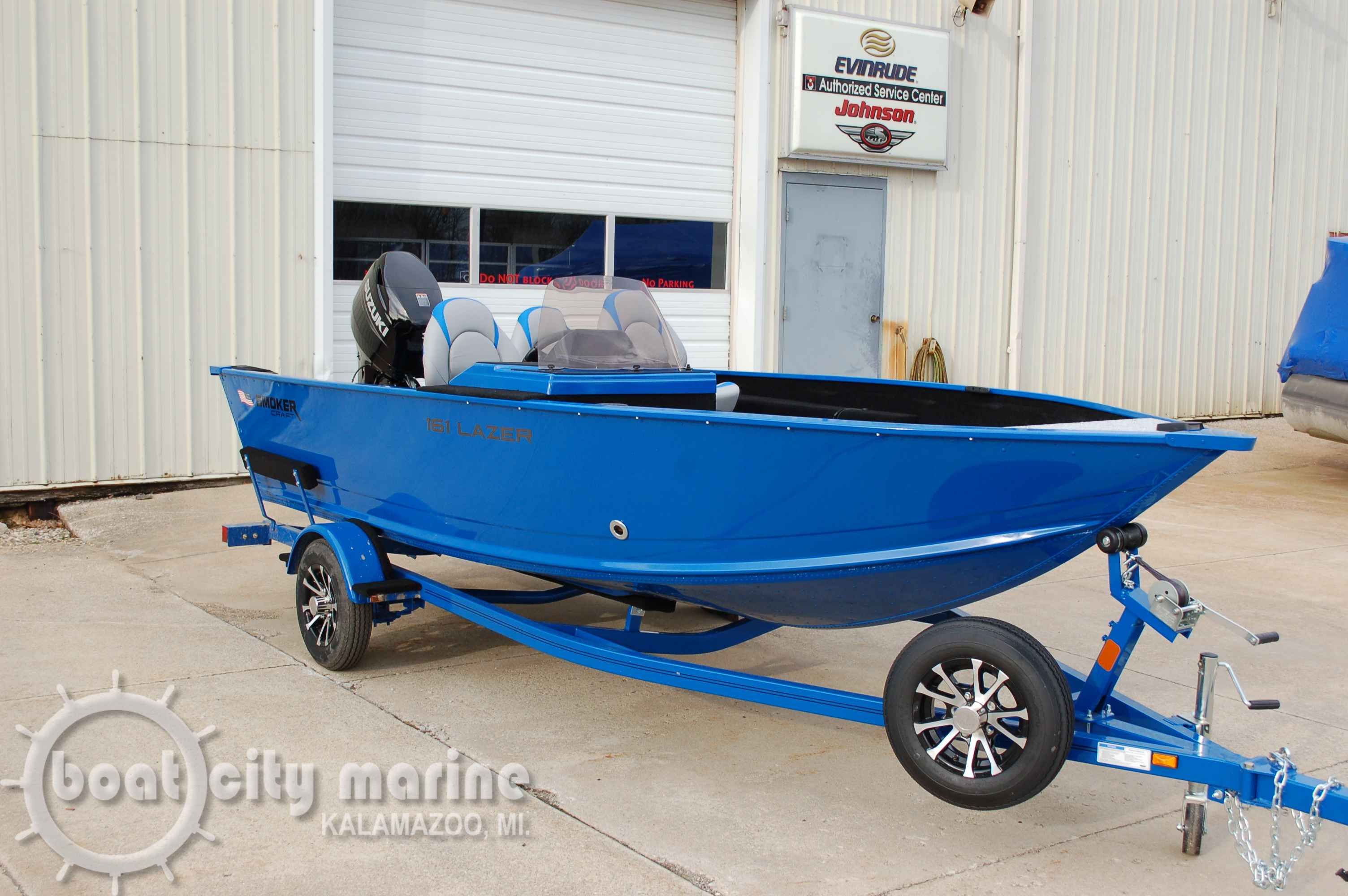 Smoker Craft Lazer 2025 Smoker Craft Lazer boat in blue on a trailer, parked outside a marine service center.