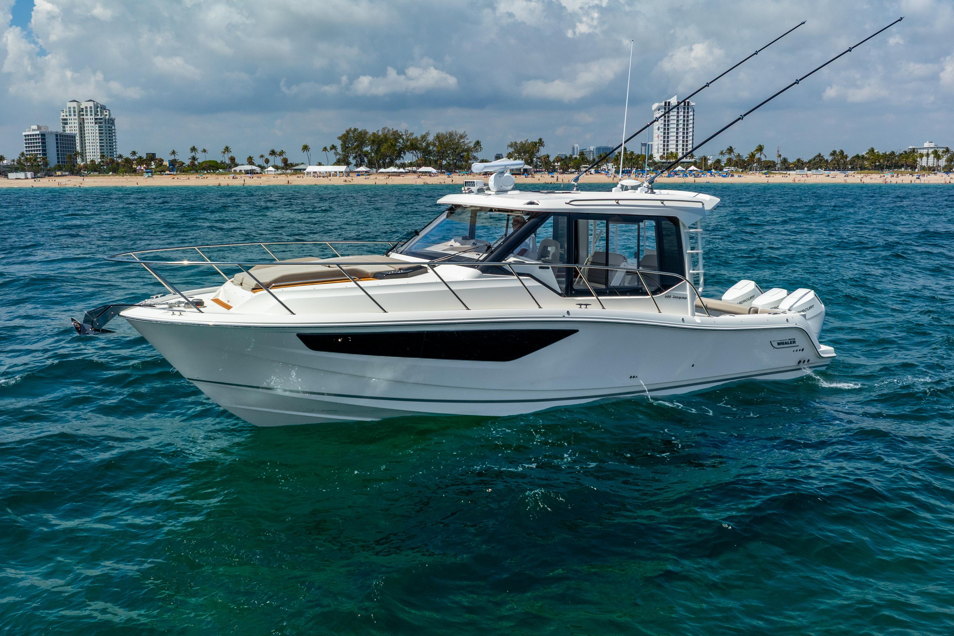 Boston Whaler 365 Conquest 2025 Boston Whaler 365 Conquest boat cruising on ocean near sandy beach.