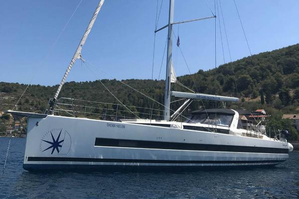 Beneteau Oceanis Yacht 62 2018 Beneteau Oceanis Yacht 62 sailing on calm waters near a forested coastline.