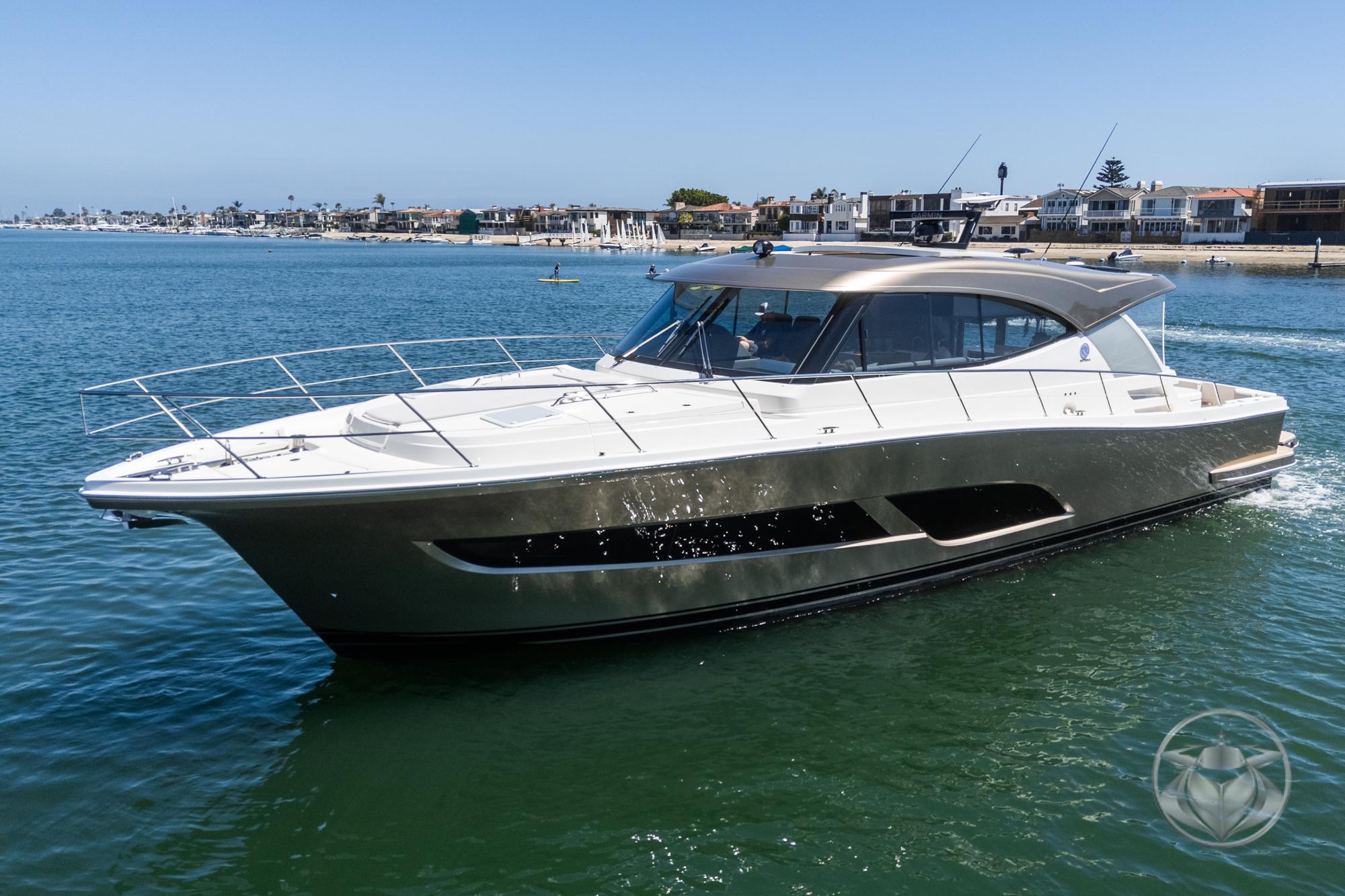 Riviera 505 SUV 2025 Riviera 505 SUV luxury yacht cruising on a sunny day near coastal homes.