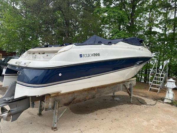 Four Winns 225 Sundowner 1998 Four Winns 225 Sundowner boat on a stand, surrounded by trees.