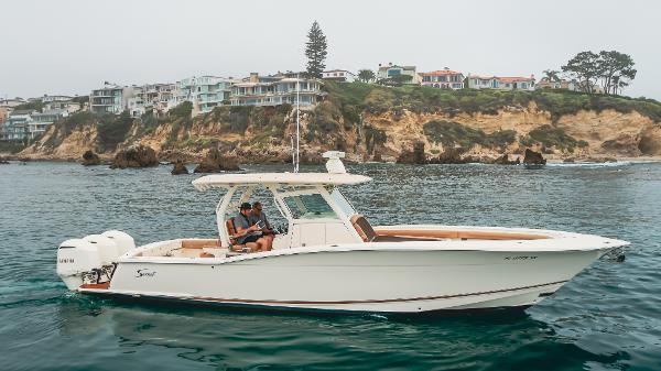 Scout 350 LXF 2016 Scout 350 LXF boat cruising near scenic coastal cliffs and luxury homes.