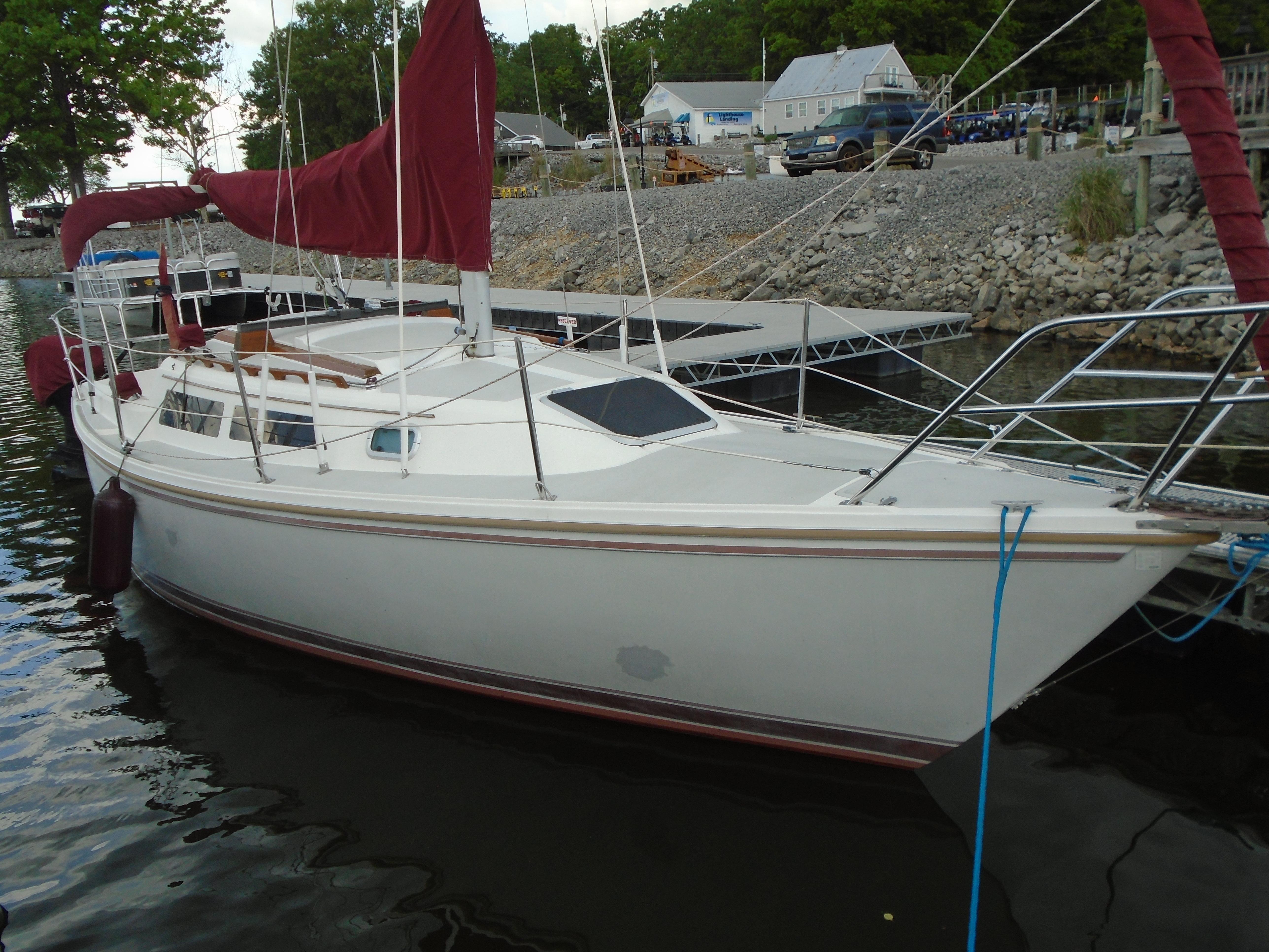 Catalina 27 1988 Catalina 27 sailboat docked at a marina with red sails and white hull.