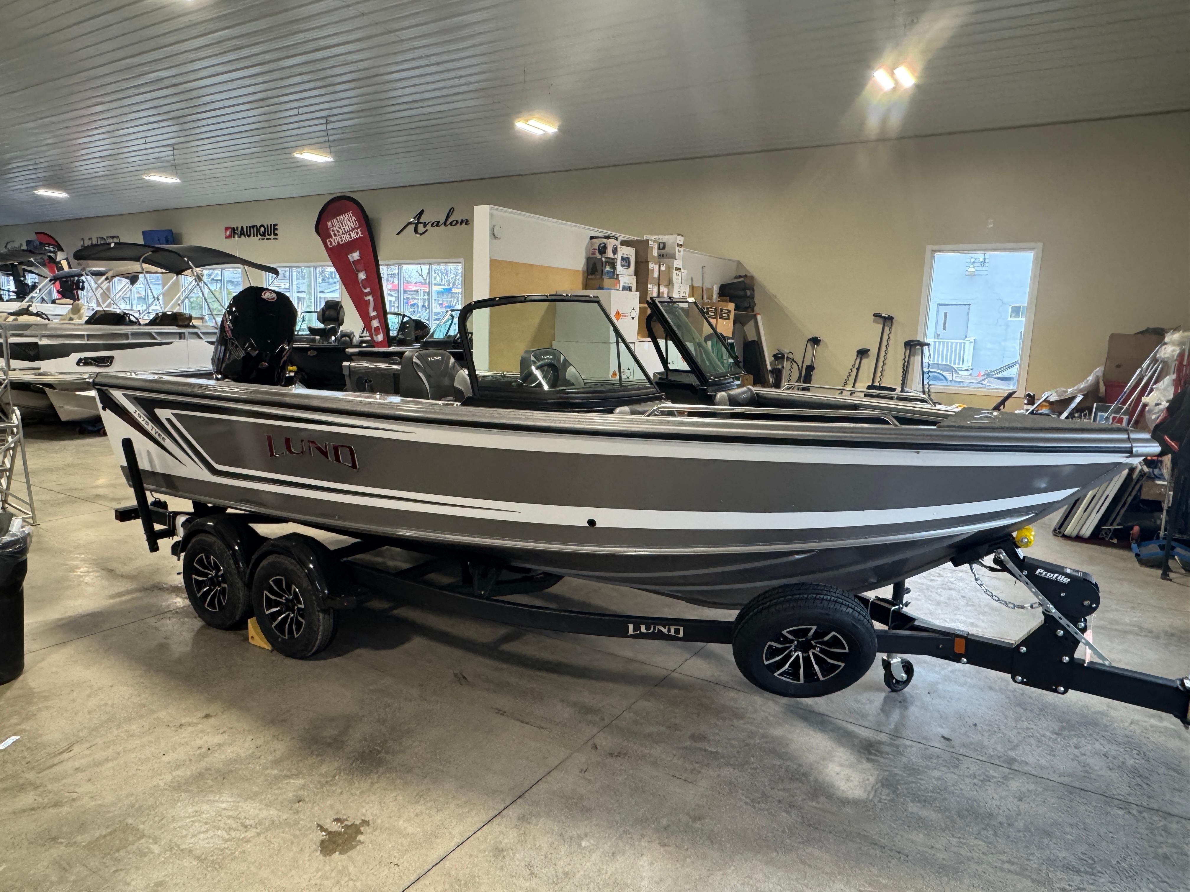Lund 1975 Tyee 2025 Lund 1975 Tyee boat on trailer in showroom, side view.