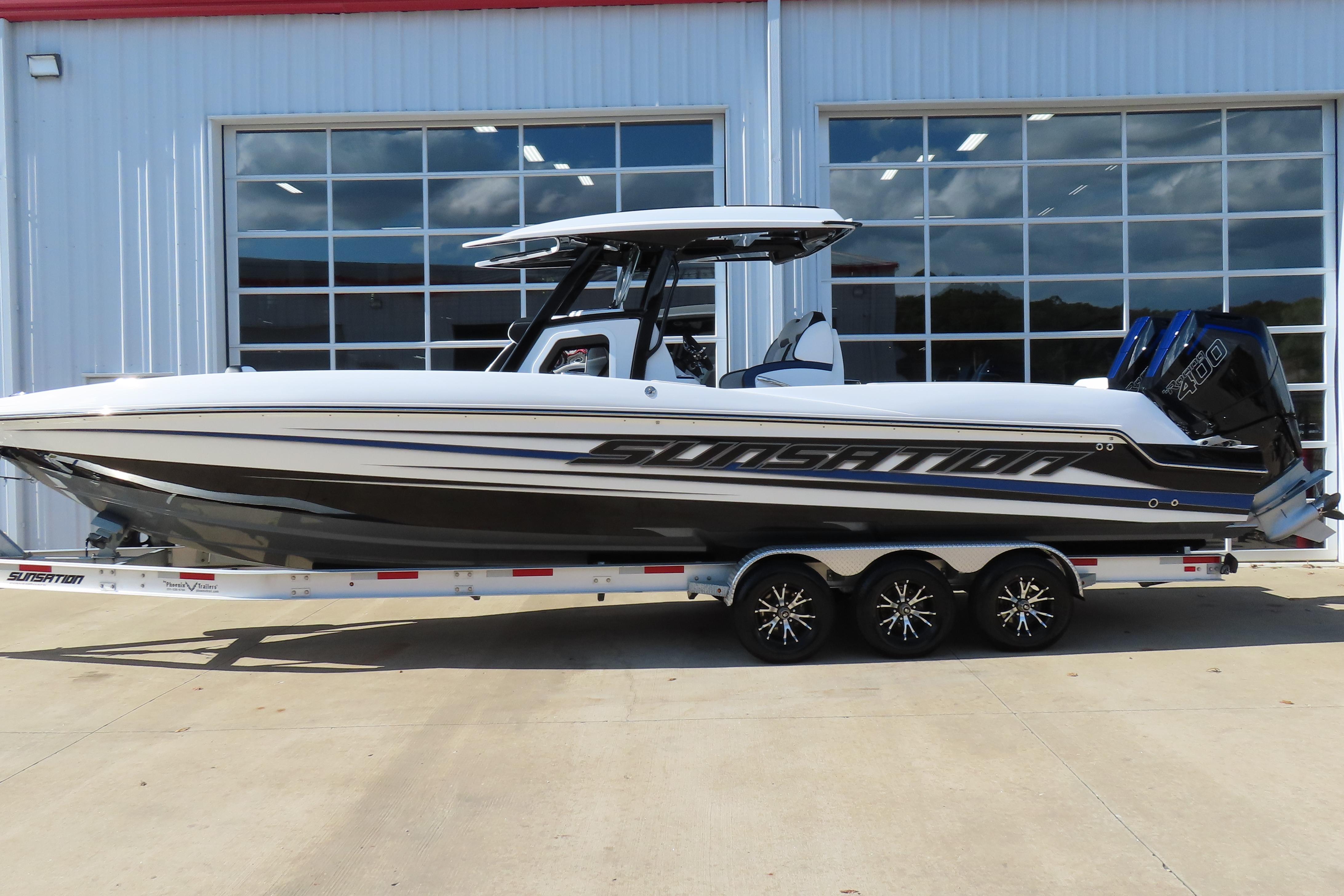 Sunsation 32CCX 2026 Sunsation 32CCX boat on trailer, sleek design, parked outside a building.