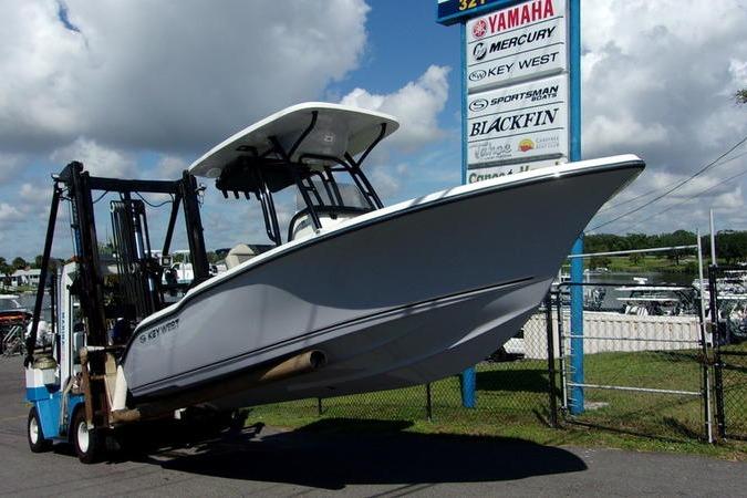 Key West 219 FS 2025 Key West 219 FS boat lifted by forklift near dealership signs.