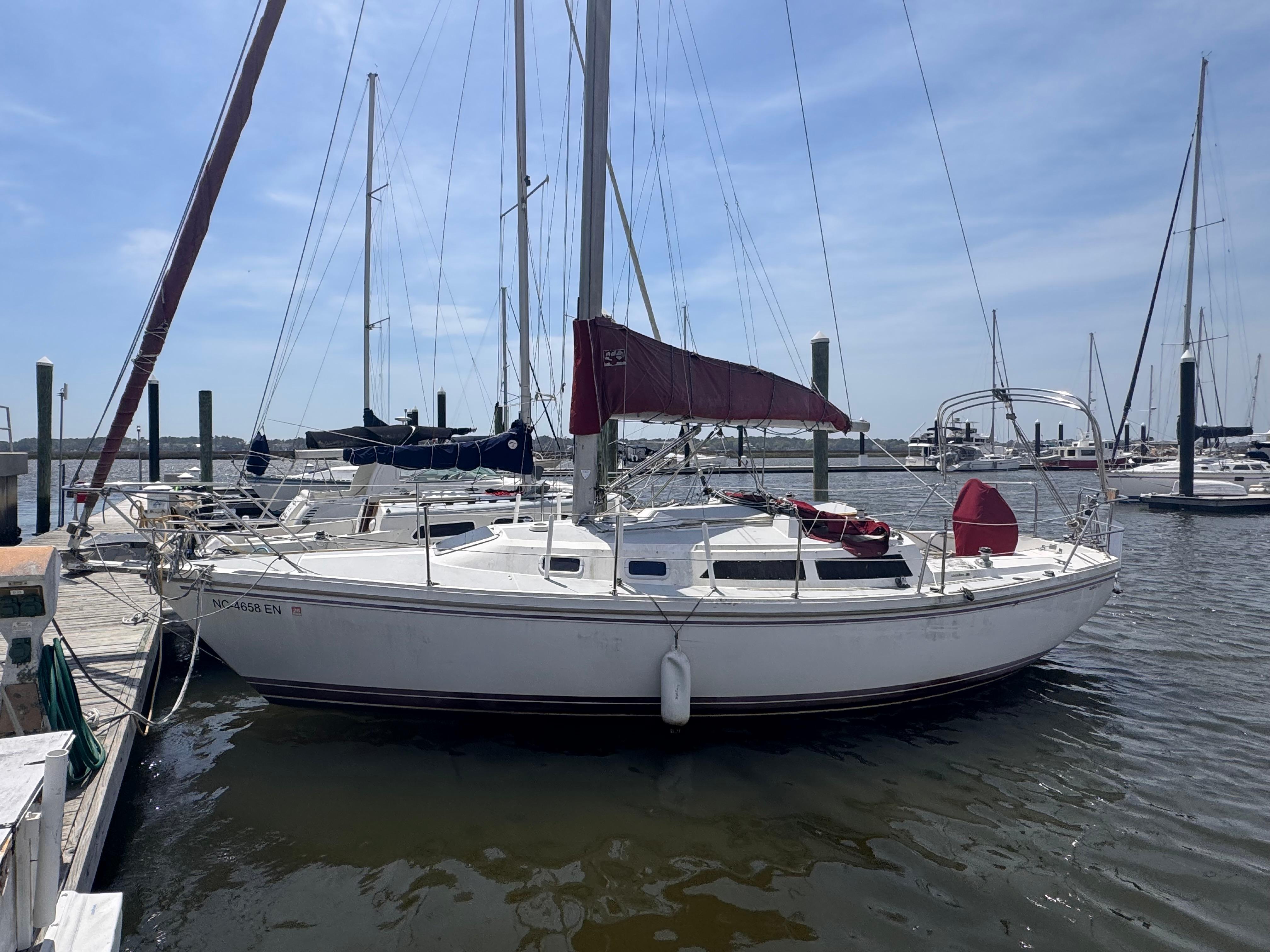 Catalina 30 Tall Rig 1990 Catalina 30 Tall Rig sailboat docked at marina, featuring maroon sail and white hull.