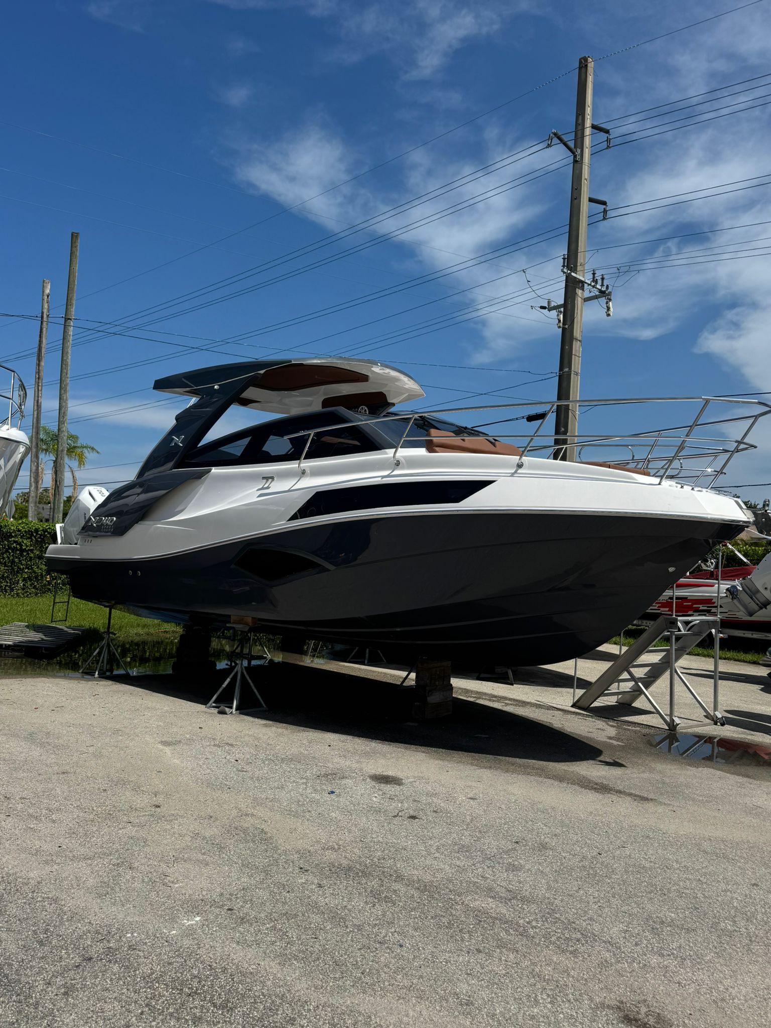 NX Boats NX340 2025 NX Boats NX340 yacht on stands, sleek design under clear blue sky.