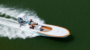 Custom Carolina 18 Flats 2023 Custom Carolina 18 Flats boat speeding on water, showcasing sleek design and performance.