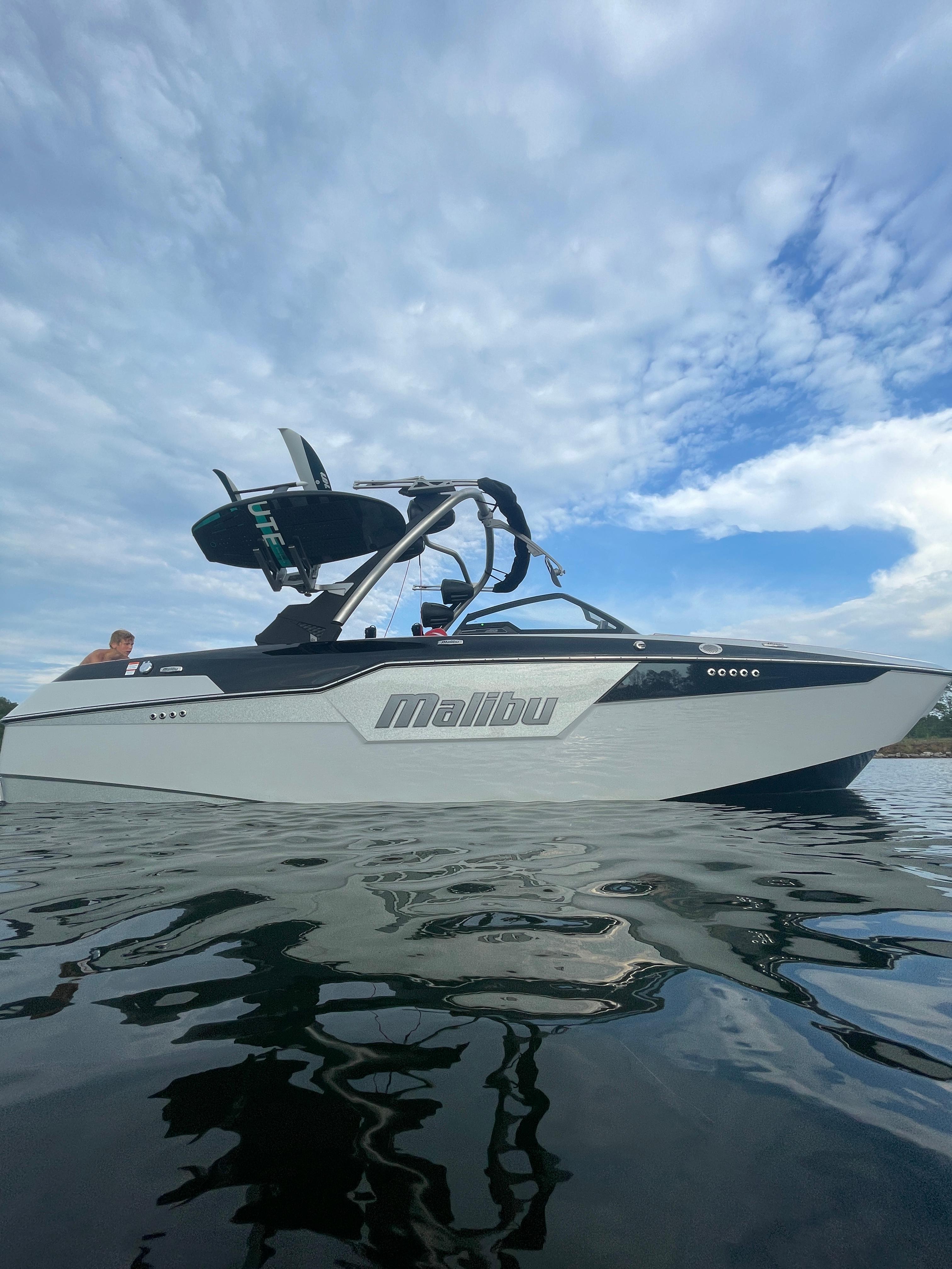 Malibu M220 2023 Malibu M220 boat on water under cloudy sky.