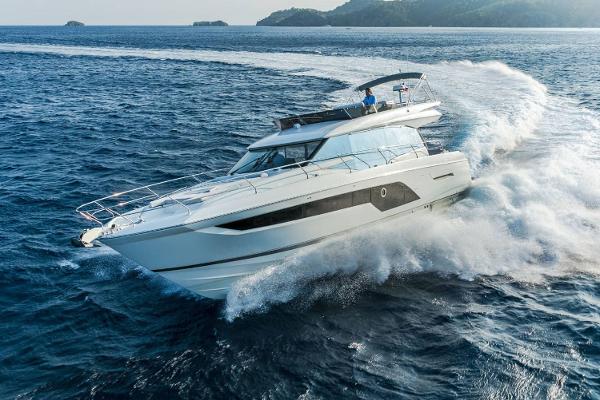 Prestige 590 Manufacturer Provided Image: 2024 Prestige 590 yacht cruising on open sea with scenic island backdrop.