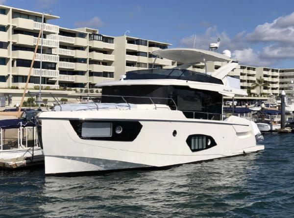 Absolute 48 Navetta 2025 Absolute 48 Navetta yacht docked at a marina with modern buildings in the background.