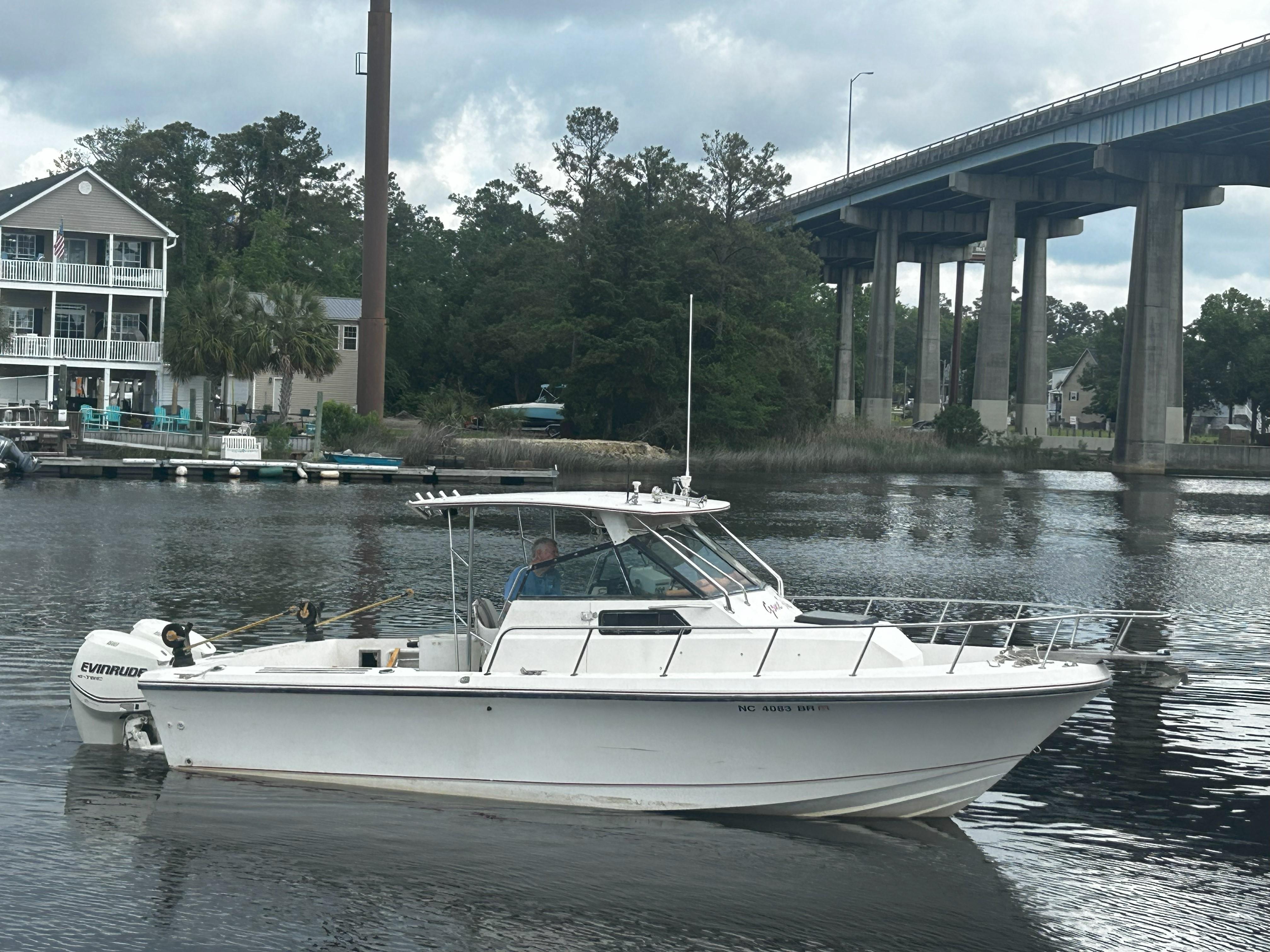 Pro-Line 239 Ultra SE 1989 Pro-Line 239 Ultra SE boat on a calm river near a bridge and houses.