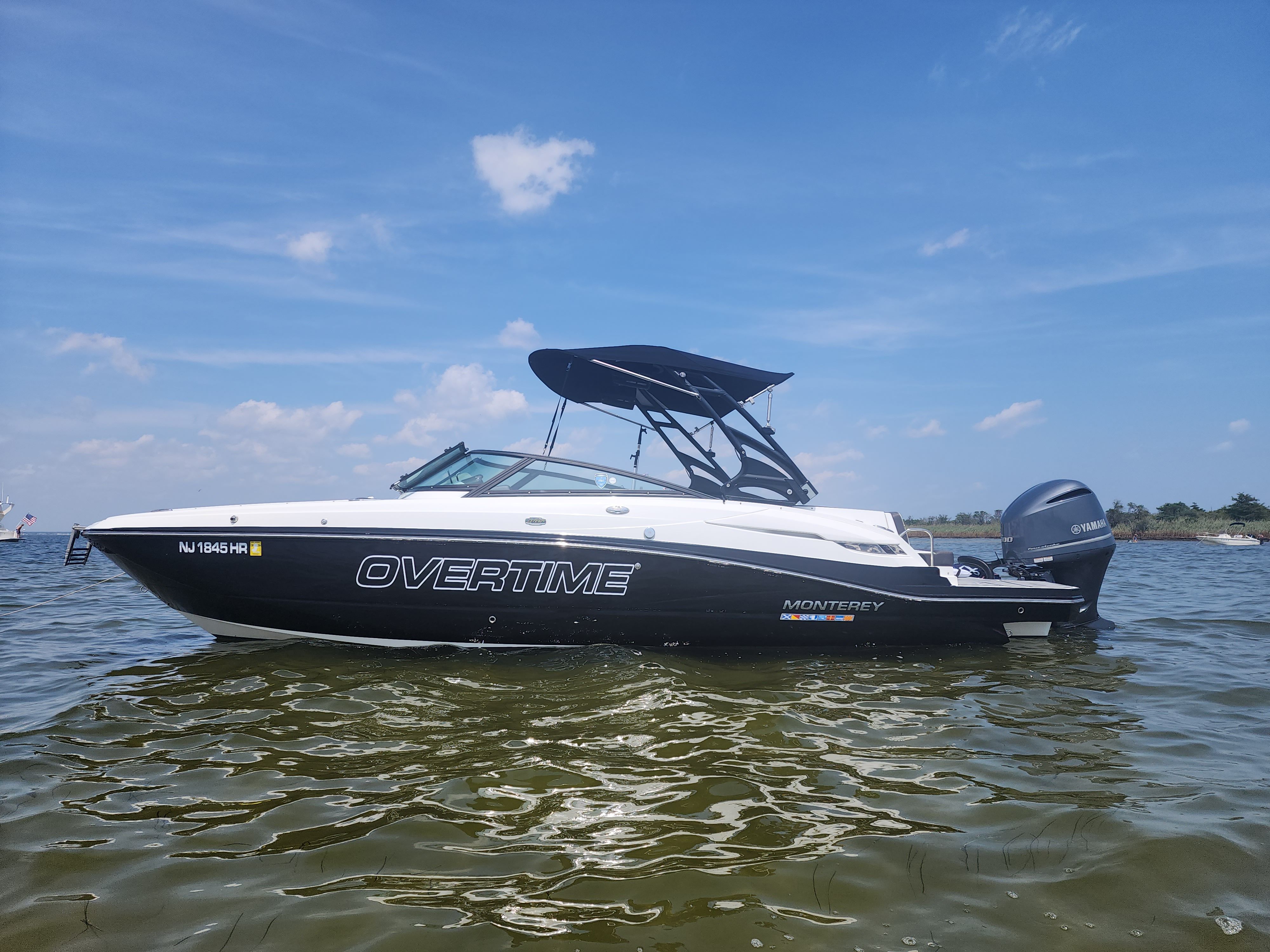 Monterey M-65 2019 Monterey M-65 boat named "Overtime" on water under clear blue sky.