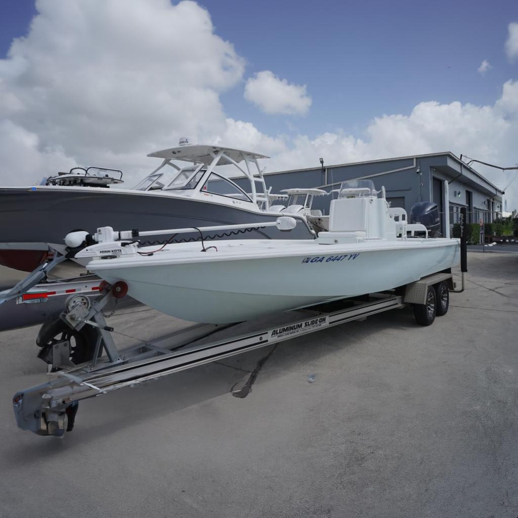 Yellowfin 24 Bay 2013 Yellowfin 24 Bay boat on trailer, parked near a building under cloudy sky.
